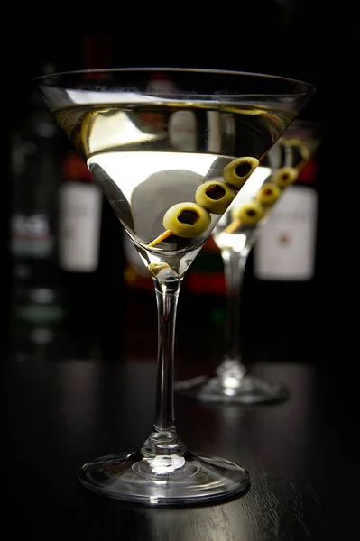 Martini-Drinks mit Oliven in Bar auf schwarzem Tisch — Stockfoto