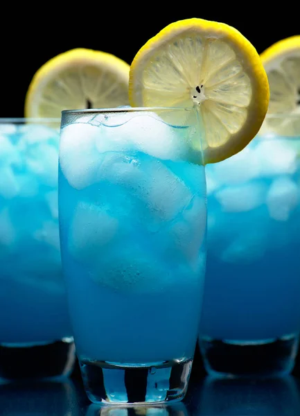 蓝色泻湖鸡尾酒与柠檬片隔离在黑色 — 图库照片