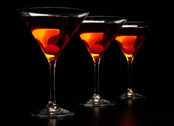Group of three manhattan cocktails in bar on black — Stock Photo, Image