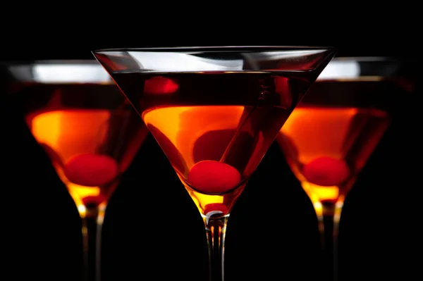 Крупным планом три манхэттенских коктейля в баре на черном столе — стоковое фото