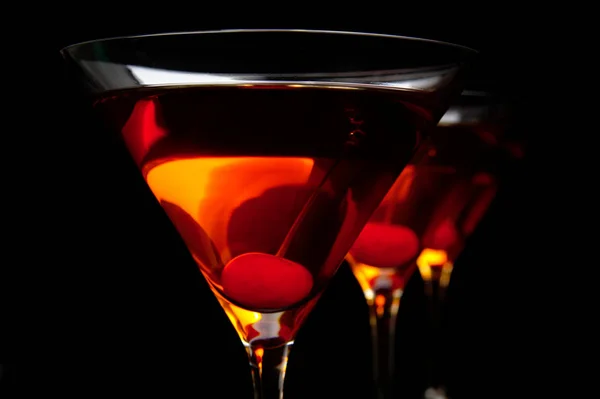 Манхэттенские напитки крупным планом с красной вишней на черном столе — стоковое фото