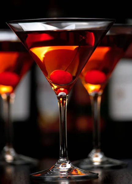 Close-up manhattan bebidas com cereja com bar no fundo — Fotografia de Stock