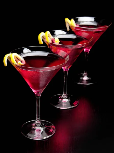 Três bebidas cosmopolitas na fila no balcão preto — Fotografia de Stock
