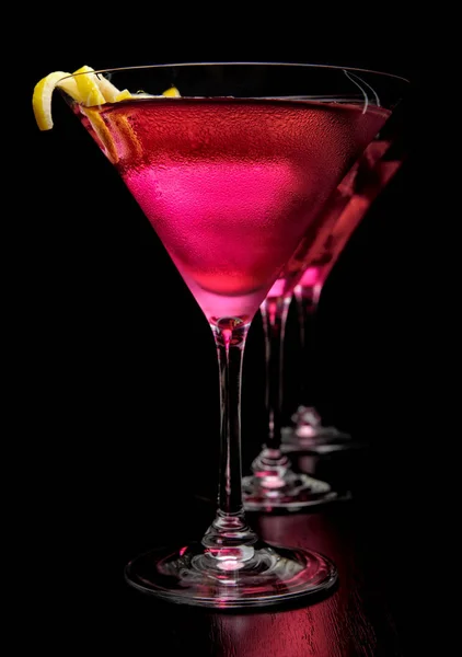 Three cosmopolitan drinks in line on black background — Stock Photo, Image