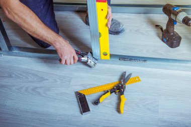 Alçıpan alçı çıpanı iş başında. Tadilat sırasında bir evde metal alçıpan inşa ederken elinde çivi çakma aleti tutan ve kullanan bir kişi