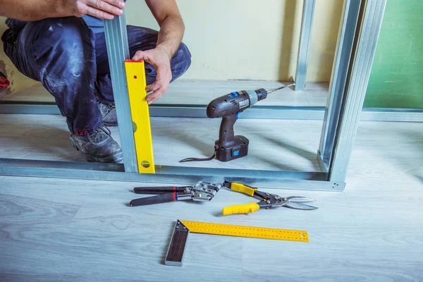 Alçıpan alçı çıpanı iş başında. Tadilat sırasında bir evde metal alçıpan inşa ederken elinde çivi çakma aleti tutan ve kullanan bir kişi