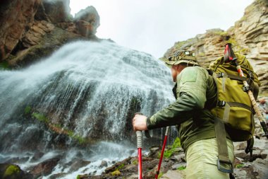 bir şelalenin arka planda bir sırt çantası ile adam turist. Turist Elbrus Dağı'na tırmanıyor