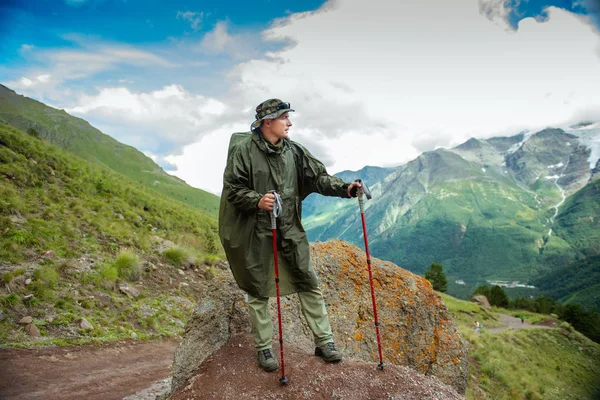 man tourist with backpack  trekking poles travels in the mountains