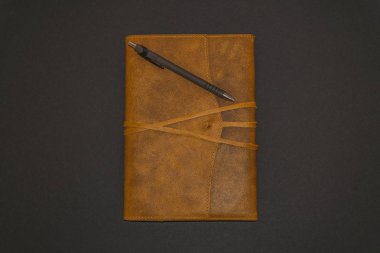 Siyah arka plan üzerine deri defter ve kalem