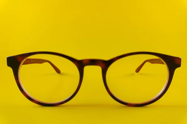 Gafas redondas de color marrón-rojo sobre fondo amarillo — Foto de Stock