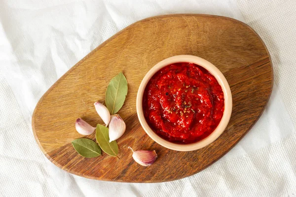 Kasede Ajvar, tahtanın üzerinde sarımsak ve baharatlı yapraklar. Sırp geleneksel yemekleri.