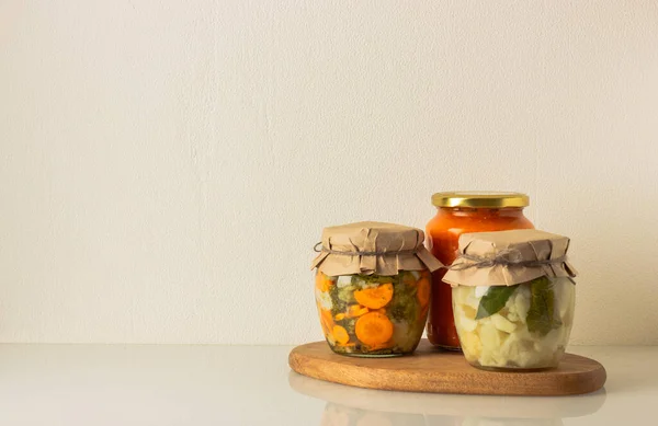 Canned vegetables in a jars: cauliflower, broccoli, carrot and zucchini in tomato sauce. — Stock Photo, Image