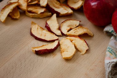 Tahtanın üzerinde kurumuş elma dilimleri ve kırmızı elmalar. Seçici odaklanma. Vegan, sağlıklı yemek..