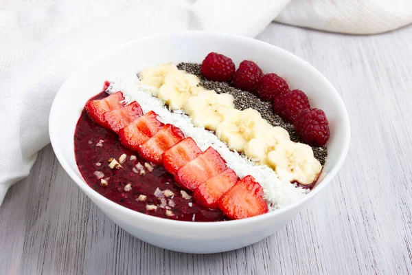 Smoothie bowl or acai berry bowl with chia seeds, strawberries, raspberries, banana slices and coconut flakes. Top view. — Stock Photo, Image