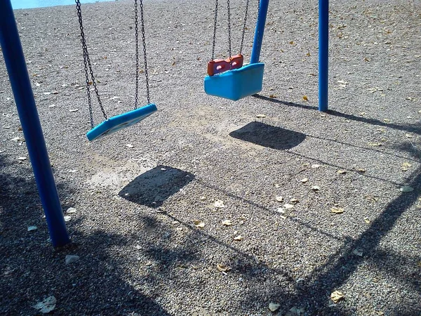 Columpio vacío en cadenas azules en la playa. Sombra en la arena. Un río —  Fotos de Stock