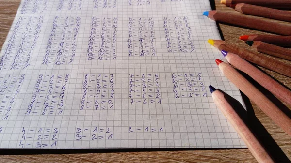 Exemplos de subtração de números são escritos em um caderno de células. Aula de matemática. Fazer trabalhos de casa — Fotografia de Stock