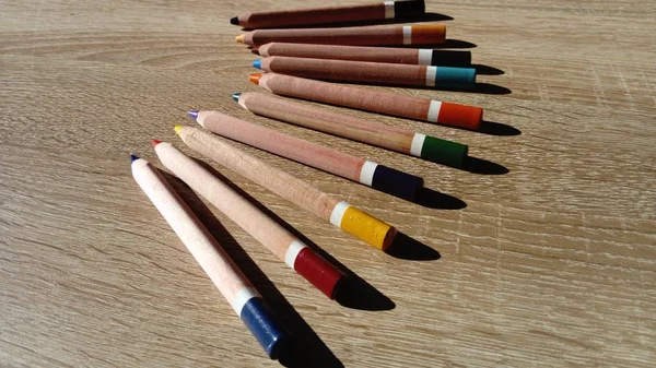Auf einem Holztisch liegen mehrere dicke Buntstifte. — Stockfoto