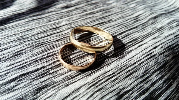 two gold rings, male and female, on a gray background