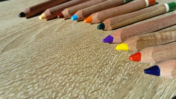 Bir bölümde üçgen şeklinde çok renkli ahşap kalemler çocuğun elince motor becerilerinin geliştirilmesi için tasarlanmıştır. Kalemler ahşap bir masanın üzerinde yatıyor. — Stok fotoğraf
