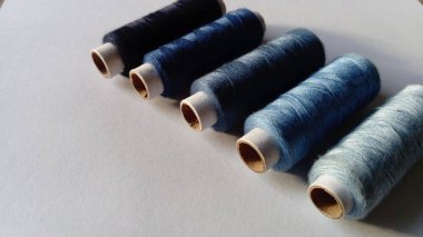 Mavinin farklı tonlarındaki iş parçacıklarının yakın çekim. Beyaz bir arka plan üzerinde bulunan iş parçacığı makaraları. Küçük Hollanda köşesi