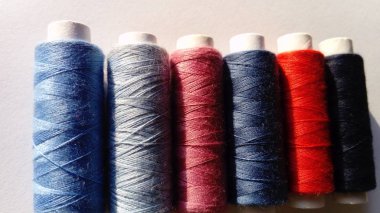 Babunlar ve farklı renklerde iplik makaraları. Beyaz arka plan. Mavi, kırmızı, pembe, gri, siyah.