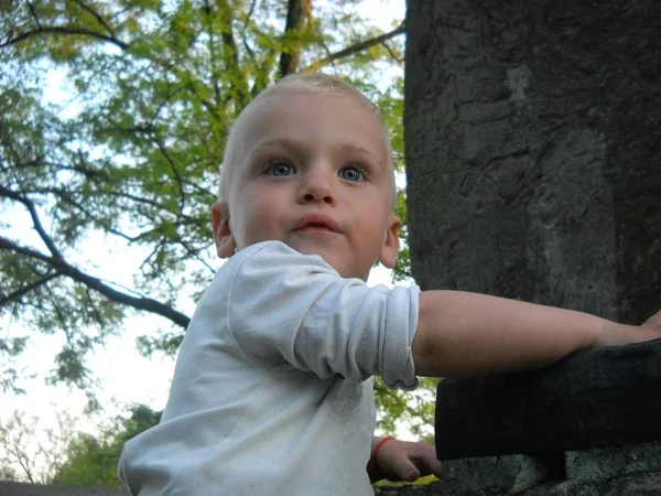 En liten pojke klättrade ett sten monument och vände huvudet till höger, uppmärksamma samtalet av sin mor — Stockfoto