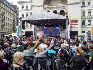 Temisoara Romanya - 6 Ekim 2019 Seyirciler opera binası yakınlarındaki eski kentin sahnesinde konserin başlamasını bekliyorlar. Kadın ve erkek kalabalıktaki arkadaşlarına el sallıyor..