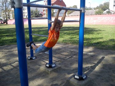 Belgrad, Sırbistan 11 Ekim 2019. Sarışın bir çocuk şehir parkındaki bir spor barında sallanıyor.