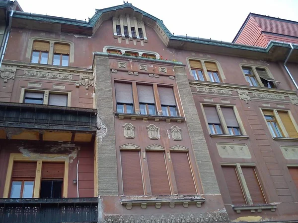 Temesvár, Románia - 2019. október 14.A régi román apartmanház külseje. Rózsaszín csempézett falak a tetőn, sok ablak redőnnyel — Stock Fotó