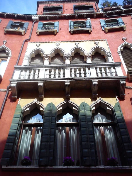 Veneza, Itália. 30 de maio de 2020. Fachada de um belo edifício veneziano. O palácio tem paredes cor-de-rosa, muitas janelas e persianas de madeira. Vista de baixo. Uma obra-prima da arquitetura veneziana . — Fotografia de Stock