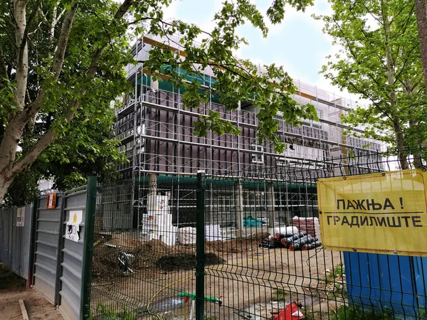 Sremska Mitrovica, Sérvia. 30 de maio de 2020. Construção de uma nova escola em Sremska Mitrovica. O edifício está em fase final de construção. Esgrima de metal. A inscrição Caution Construction . — Fotografia de Stock