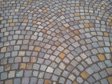 Şehir meydanında eski kaldırım taşları. Gri ve bej taşlar. Yarı daireler ve yuvarlak çizgiler.