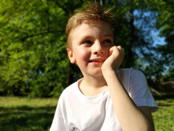 Rapaz Olha Para Distância Pensa Sorri Criança Apoiou Queixo Mão — Fotografia de Stock