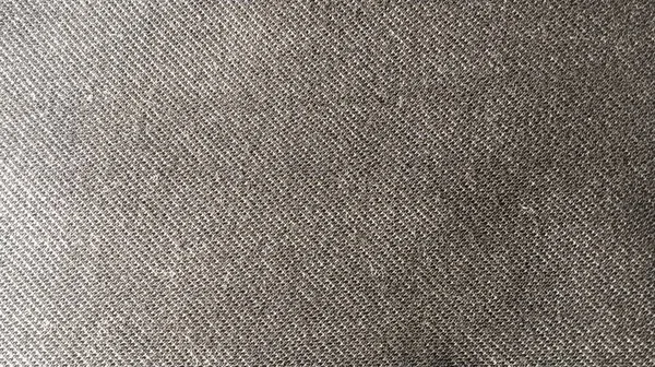 Gray fabric close-up. Weaving of individual threads. Knitted polyester. Material for sewing toys, home and childrens clothing. Low pile synthetic fiber. Lattice. Gradient. Lighting left