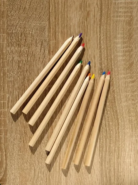 木制背景上铅笔的顶部视图 办公室文具 学生的学习用品 教育和创造力的概念 铅笔的三角形横截面 五颜六色长铅笔 — 图库照片