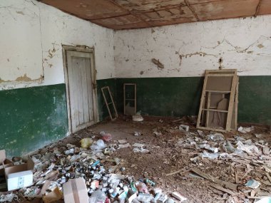 Sırbistan, Belgrad, 10 Mayıs 2020. Terk edilmiş evin içinde. Grunge sahnesi. Yere saçılmış çöp. Duvarlarda yeşil boya var. Beyaz yarım duvar. Ahşap pencere çerçevelerine ateş etmiş. Şişeler, kağıt parçaları..