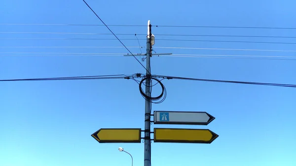 右指向空白的白色方向标志 路标指示标志 黄色和白色箭头是道路上或交叉口的标志 背景是蓝天 环绕着电线 — 图库照片