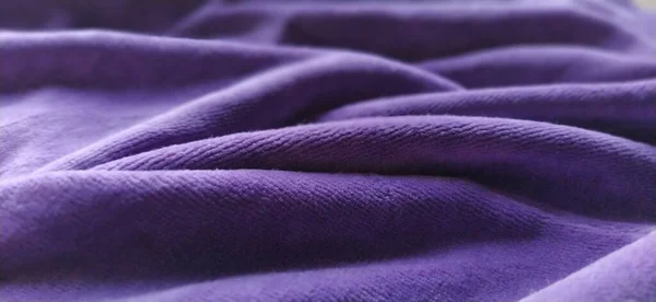 Fabric sheer curtain fabric. Beautiful violet color. Soft velvet with a pile. The curtain material is carelessly folded and wrinkled on a horizontal surface. Fabric sample. Interior design option