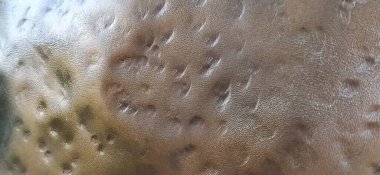 Bronz metal yüzey. Çizik, oyuk ve göçüklerle oluşmamış metal doku. Kırmızı, kahverengi, turuncu, bronz tonlar. Metal döküm. Donanım.