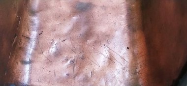 Bronz metal yüzey. Çizik, oyuk ve göçüklerle oluşmamış metal doku. Kırmızı, kahverengi, turuncu, bronz tonlar. Metal döküm. Donanım.