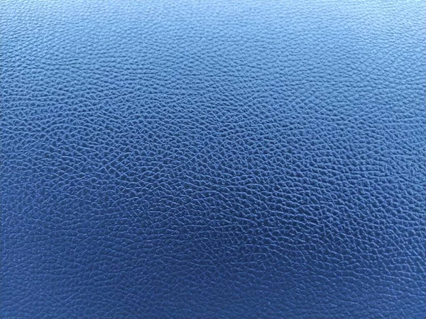Blue leather background with rich texture. Close-up of artificial gray leather. A blurred background around the edges of the image.