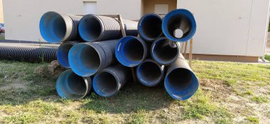 Sremska Mitrovica, Sırbistan, 23 Ağustos 2020. Metal kıvrımlı borular, içi mavi. Tesisat ya da ısıtma boruları bir yerleşim yerinin yanında yatar. Oluklu metal. Teknik ve inşaat borularının üretimi