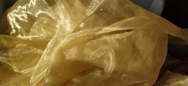 Organza, bej rengi parıltılı sarı-kahverengidir. Parlak, yansıtıcı, perdeler ve tüller için güzel kumaş. İç tasarım seçeneği. Bükülmüş, gelişigüzel katlanmış organza. Pankart.