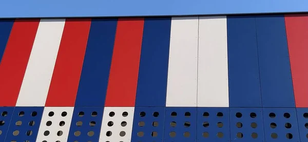Geometric colored elements of the building facade with planes, lines and holes. Abstract background and textures in red, blue and white colors. Metal profile covering load-bearing building structures