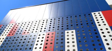 Modern bir binanın cephesi. Kırmızı, mavi ve beyaz levhalar ya da dekoratif delikli metal profiller. Dış yüzeyde teknolojik çözümler. Dekoratif elementler altında destekleyici yapılar inşa ediliyor.