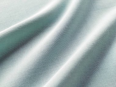 Güzel katlanmış açık yeşil kumaş. Tekstil üzerinde yumuşak hoş dalgalar ve fırfırlar. Yakın plan. Perdeler için kumaş, terzilik ya da döşeme için kumaş.