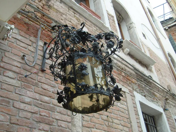 Eiserne Lampe vorhanden. Vintage geschmiedete venezianische Straßenlaterne. Zarte Metalldekorationen. Im Hintergrund eine Ziegelwand eines Hauses — Stockfoto