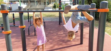 Sremska Mitrovica, Sırbistan, 13 Eylül 2020. Bir erkek ve bir kız spor ya da oyun alanında fiziksel egzersizle meşgul olurlar. Beyaz tişörtlü bir çocuk. Çizgili elbiseli kız gülüyor.