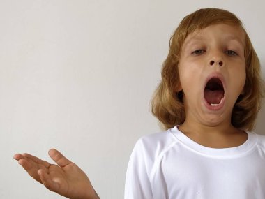 6-7 yaşlarında tatlı bir kız uyumak istiyor. Bronz tenli ve beyaz saçlı bir çocuk. Beyaz tişört. Uzayı kopyala Çocuk senin ellerinle ağzını kapamadan esniyor..