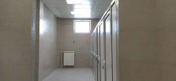 Sremska Mitrovica Service September 2020 学校の新しい公衆トイレ 壁にベージュのセラミックタイル カメラの向かいに明るい窓 暖房用バッテリー 白い扉のトイレの個室 — ストック写真